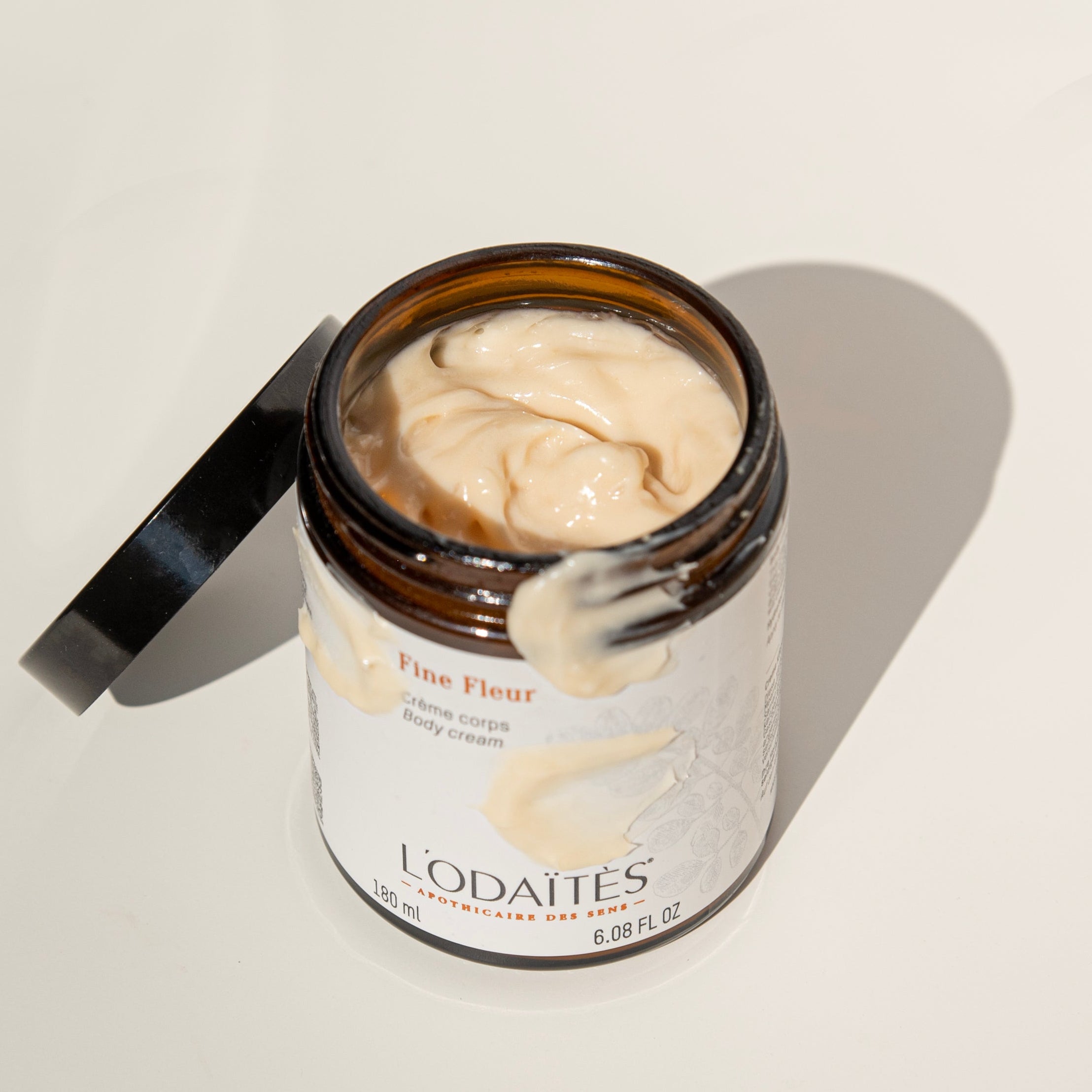 Pot ouvert de crème corps Fine Fleur de L'Odaïtès avec de la texture sur le pot