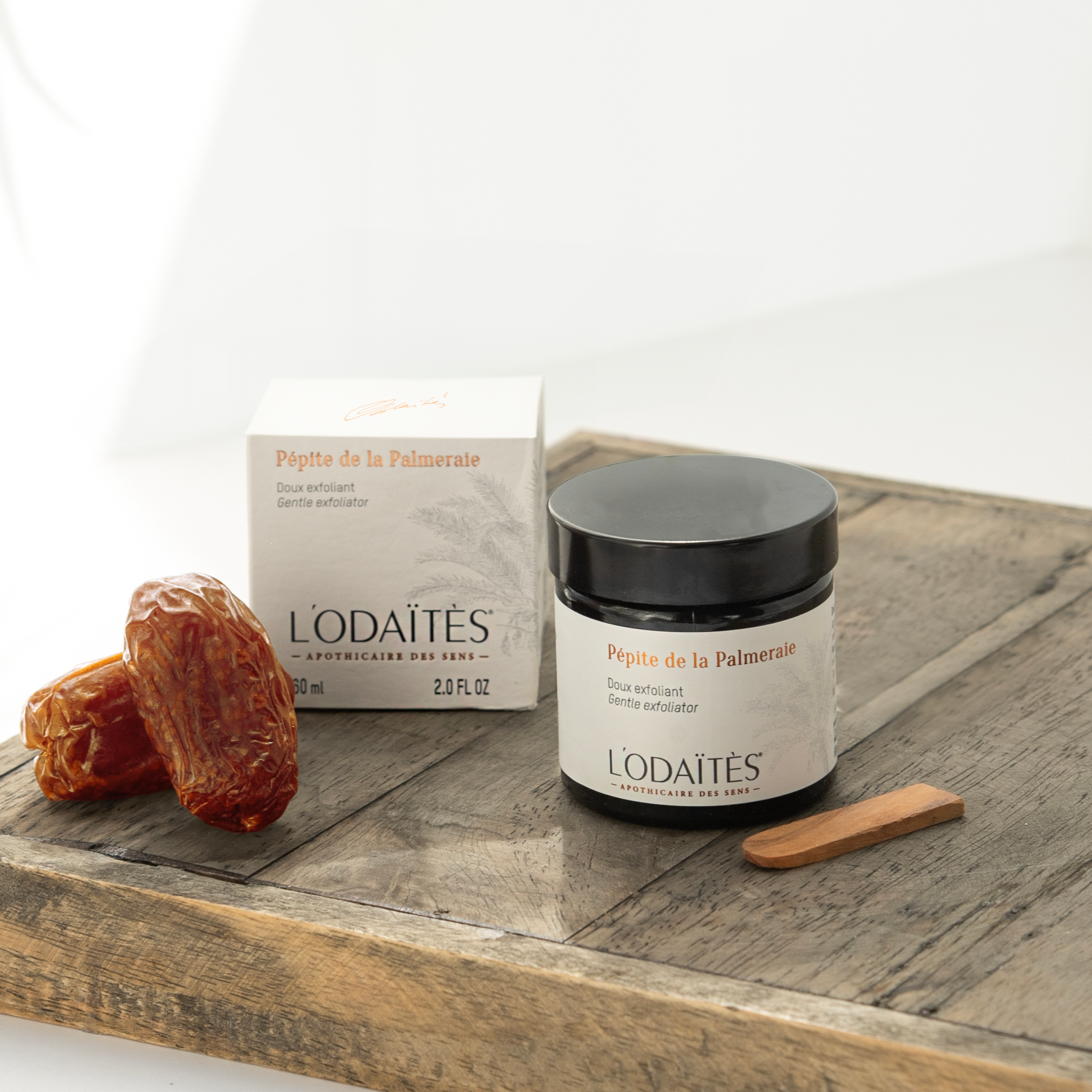 Doux exfoliant Pépite de la Palmeraie de L'Odaïtès sur un plateau en bois avec son étui et des dattes