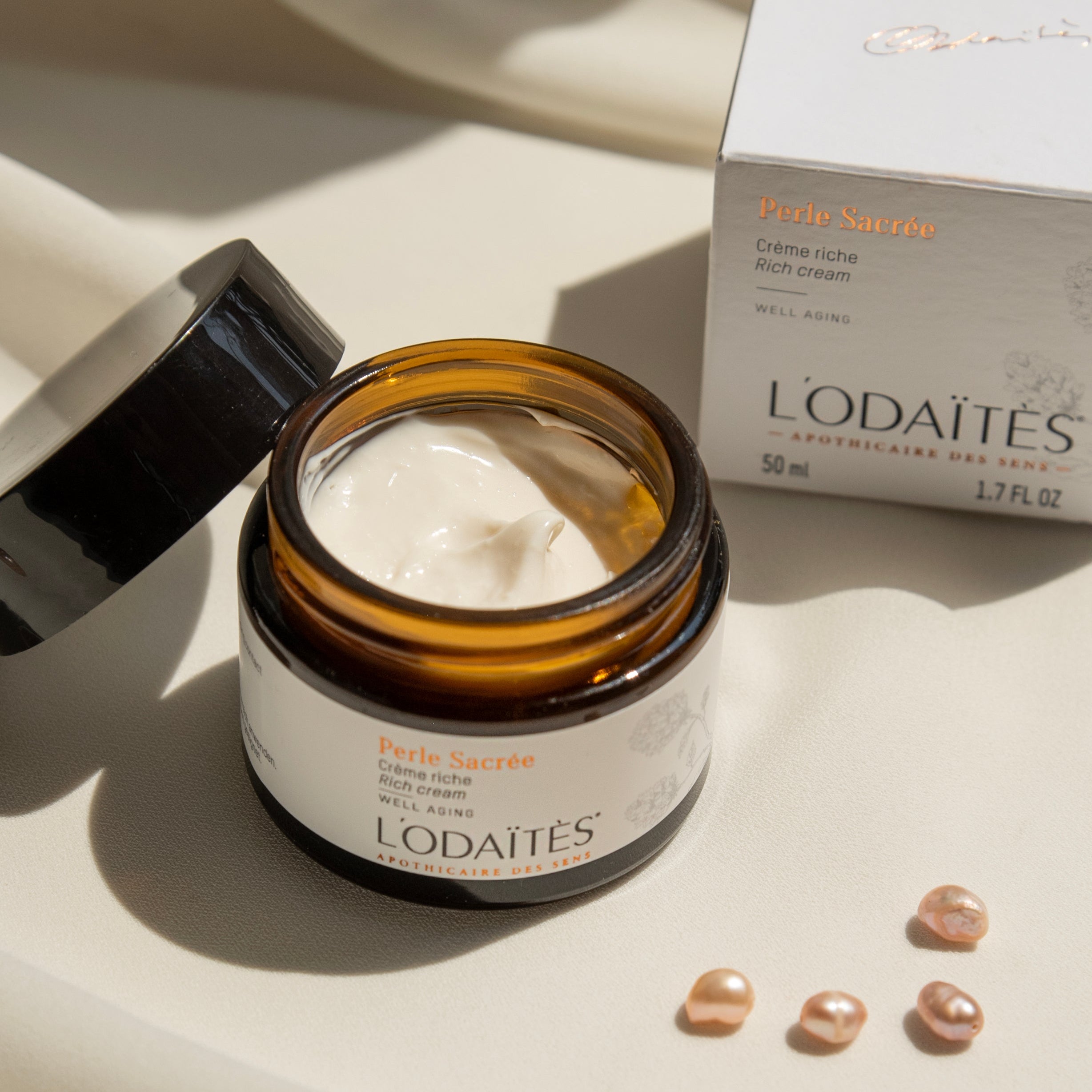 Pot ouvert de crème riche Perle Sacrée L'Odaïtès avec des perles