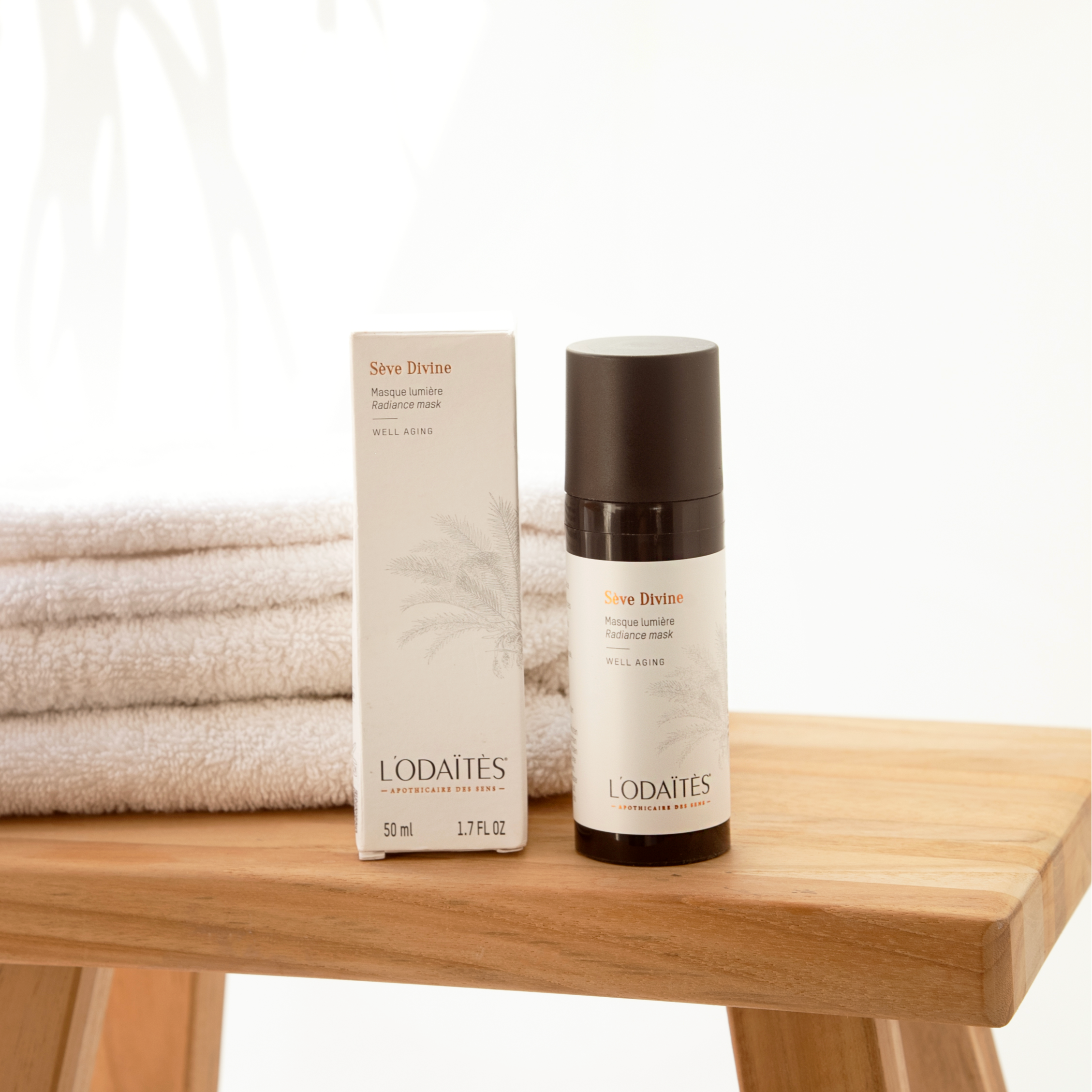 Masque lumière well-aging Sève Divine de L'Odaïtès posé sur un tabouret en bois avec son étui et des serviettes